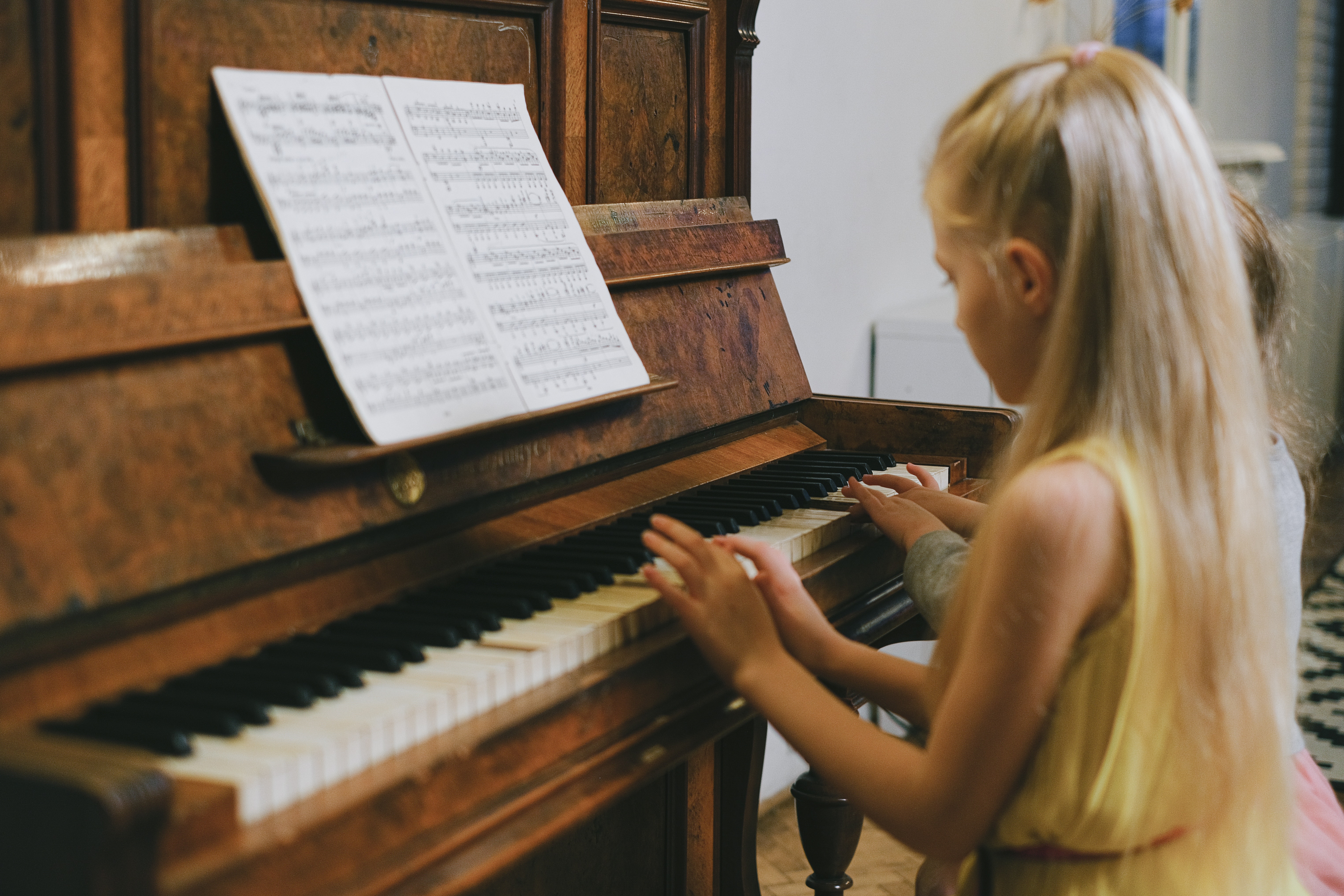 bambina suona al pianoforte con spartito